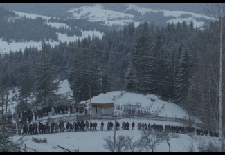 A procession of Ukrainian civilians amid snow-covered hills, attending the funerals of soldiers killed defending the country against the Russian invasion