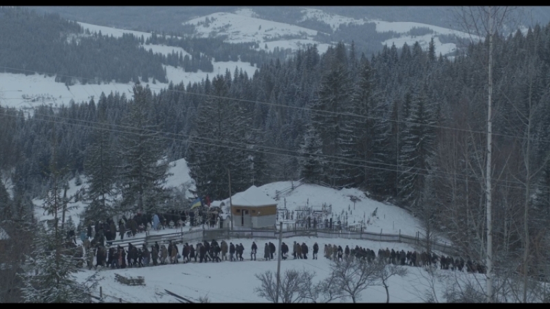 A procession of Ukrainian civilians amid snow-covered hills, attending the funerals of soldiers killed defending the country against the Russian invasion