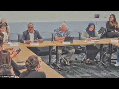 A group of people seated around a conference table, engaged in discussion at a meeting.