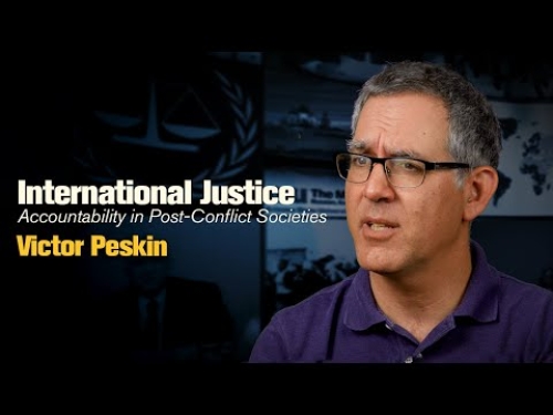 Man in glasses speaking, with text: "International Justice: Accountability in Post-Conflict Societies, Victor Peskin" on a dark background.
