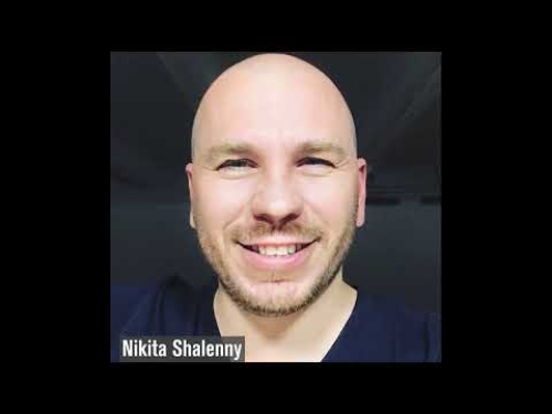 Smiling person with a shaved head against a dark background. Text in corner reads "Nikita Shalenny."